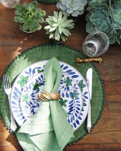 a place setting with green napkins and succulents