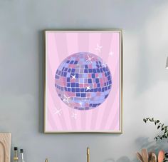 a framed art print of a disco ball on a pink wall above a kitchen sink