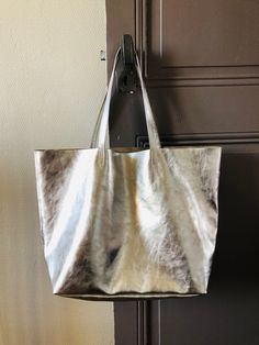 Luxurious Silver Leather Tote Bag Fall in love with this sumptuous silver leather tote bag! This stunning bag is perfect for any occasion, whether day or night. Featuring a gorgeous brut unlined design, it is both chic and functional, complete with a spacious inside zipper pocket to keep your essentials secure. Light and airy, this tote shines with elegance and is the ultimate arm candy for any outfit! Dimensions: 48 x 32 x 16 cm Shoulder Handles: 50 cm Customization Options: If you're looking f Silver Leather Tote Bag, Silver Bag, Metallic Leather Bag, Grey Tote Bags, Leather Glasses Case, Grey Tote, Silver Bags, Oversized Bag, Oversized Tote Bag