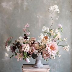 a vase filled with lots of flowers sitting on top of a wooden table next to a book