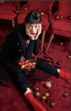 a woman is sitting on the floor with christmas ornaments around her and holding her hand to her face