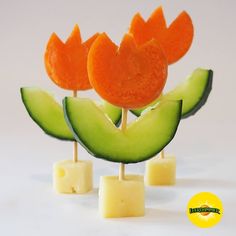 three pieces of fruit with slices of cheese on them and one piece cut in the shape of flowers