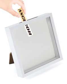 a person is holding up a small white box with a gold stick in it's mouth