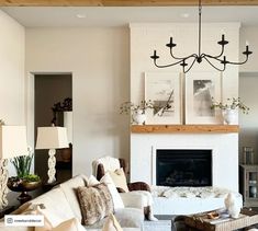 a living room filled with furniture and a fire place under a chandelier in front of a fireplace