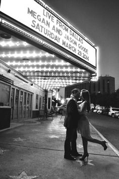 a man and woman kissing in front of a theater