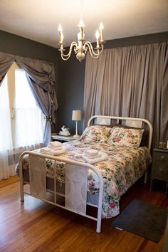 a bedroom with a bed, chandelier and window in the corner is shown