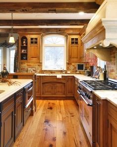 a large kitchen with wooden cabinets and white counter tops, along with hardwood flooring