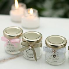 four small jars with candles in them sitting on a table