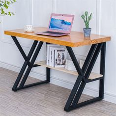 a laptop computer sitting on top of a wooden desk next to a plant and bookshelf