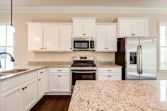 a kitchen with white cabinets and granite counter tops