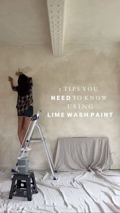 a woman standing on top of a ladder in front of a wall with the words,'this you need to know us using lime wash paint '