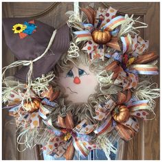 a wreath with a scarecrow face on it and a hat hanging from the front door