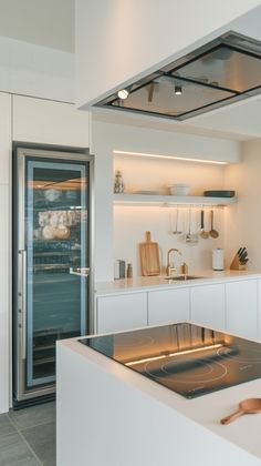 a modern kitchen with stainless steel appliances and white cabinets, along with an open glass door leading to the outside