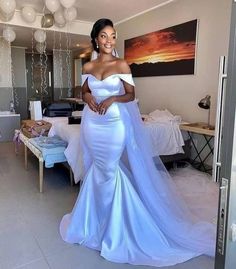 a woman in a white wedding dress standing next to a bed with balloons hanging from the ceiling