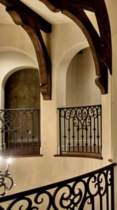 an iron balcony railing with wooden posts and arched windows