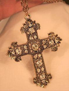 This goldtone necklace features a gorgeous mid-to-large-sized pectoral cross pendant with lots of sparkle and shine!  It has a lacy filigree finish with faceted white/clear crystal rhinestones that capture the light beautifully!  The reverse has a shiny finish and it is in new condition.  It is a larger piece, with a substantial weight and quality, measuring 2 3/4 inches wide and 3 1/2 inches long.  The chain is 24 inches and closes with a safety catch. Gold Cross Pendant Jewelry For Party, Gold Cross Necklace For Party, Gold Rhinestone Cross Pendant Necklace, Elegant Rhinestone Cross Pendant Necklace Gift, Elegant Cross Rhinestone Necklace Gift, Elegant Rhinestone Cross Necklace As Gift, Elegant Cross Rhinestone Necklace For Parties, Elegant Cross Rhinestone Necklace For Gift, Elegant Cross-shaped Rhinestone Necklace As Gift