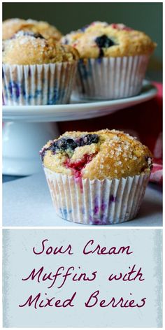 blueberry muffins with mixed berries are on a white plate and the title reads, sour cream muffins with mixed berries