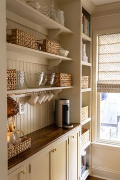 a kitchen with white cupboards and shelves filled with dishes, cups and other items