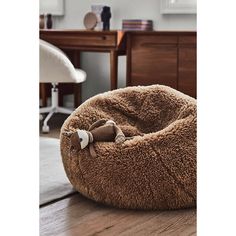 a brown dog bed with a bow on it's head sitting on a wooden floor