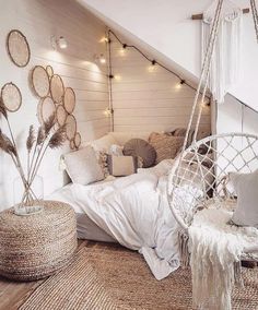 a bedroom with white bedding and hanging decorations on the wall, including a hammock chair