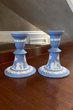 two blue candlesticks sitting on top of a wooden table