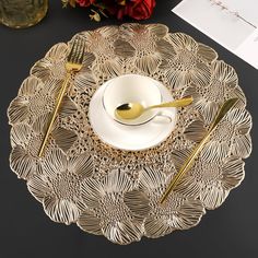 a place setting with gold colored utensils on a black tablecloth and red roses