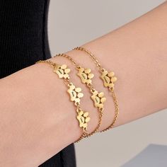 a close up of a person's arm wearing gold bracelets with butterflies on them