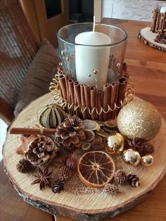 a candle that is sitting on top of a wooden table next to ornaments and pine cones