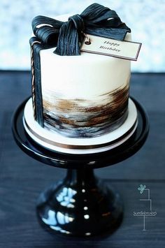 a white and black cake with a bow on top