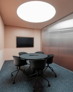 a conference room with round table and black chairs in front of a flat screen tv