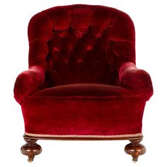 a red velvet chair with gold trimmings on the legs and foot rests against a white background