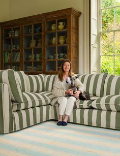 a woman sitting on top of a couch holding a dog