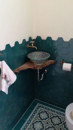 a bathroom with green walls and blue tiles on the floor, along with a white toilet