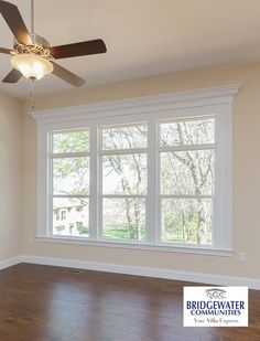 an empty living room with wood floors and ceiling fan in the middle of the room