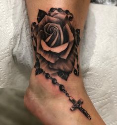 a black and white rose with a cross tattoo on the foot