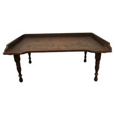 an old wooden tray with ornate carvings on the top and legs, sitting on a white background