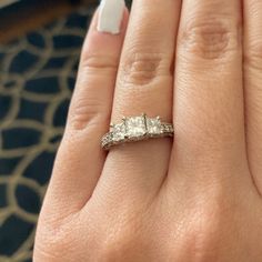 a woman's hand with a three stone ring on top of her finger,