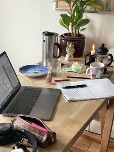 an open laptop computer sitting on top of a wooden table next to a cup and coffee mug