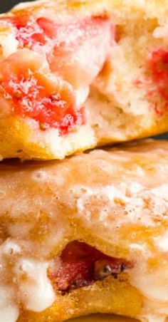 two strawberry shortcakes with icing and powdered sugar on top are stacked together