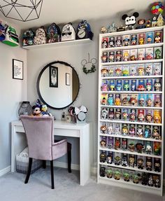 a room with a desk, mirror and shelves filled with cartoon figurines on the wall