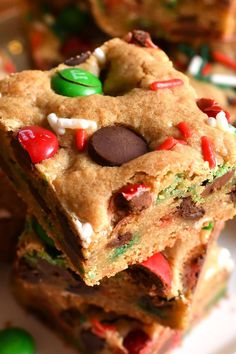 a stack of cookies and candy bars sitting on top of a white plate next to green candies