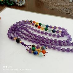 Handmade/Handcrafted ｡.｡  ｡.｡ Number of beads: 108 Beads Guru bead  Size of 10MM  Mala Bead Size: 8 mm Tassel height: 3 Inches ｡.｡  ｡.｡ »»--------><--------«« IF worn on your neck as a  necklace, it will have a length of around 45 cm / 18 inches; the length of the whole mala is around 95 cm / 38 inches.Chakra Colors Let's look at the 7 Chakra colors: 1- RED - The Root Chakra 2- ORANGE - The Navel or Sacral Chakra 3- YELLOW - The Solar Plexus Chakra 4- GREEN - The Heart Chakra 5- BLUE - The Throat Chakra 6- INDIGO - The Third Eye Chakra 7- VIOLET - The Crown Chakra This necklace measures  approx 21 Inches 54 cm Bids size - 8mm approx 108 Beads/  Natural Amethyst Seven Chakra Japa Mala Prayer Beads Blue colour Round Beads Japa Mala Guru bead Necklace semi-precious Gemstone Round Beads // Lon Traditional Purple Beaded Necklace With Round Beads, Round Gemstone Beads For Meditation, 8mm Amulet Beads For Healing, Spiritual Multicolor Amethyst Beaded Bracelets, Multicolor Amethyst Beaded Bracelets For Spiritual Wear, 8mm Healing Amulet Beads, Multicolor Beaded Spiritual Crystals, Bohemian Amethyst Gemstone Beads Crystal Necklaces, Bohemian Amethyst Gemstone Bead Crystal Necklace