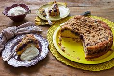 a cake on a yellow plate next to two plates with ice cream and other desserts