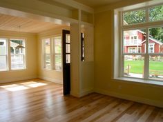 an empty living room with wood floors and large windows