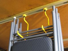 two yellow handles are attached to the back of a gray luggage bag on a rack