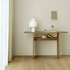 a table with some books on it and a vase next to it in the corner