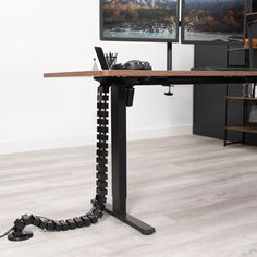 a computer desk with two monitors on top of it and a metal chain around the base