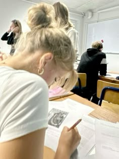 a woman sitting at a desk in front of a class room filled with other people