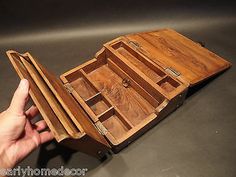 a hand holding an open wooden box with compartments