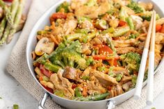 a pan filled with stir fry vegetables and chopsticks